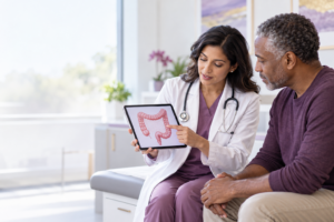 Gastroenterologist discussing colorectal cancer screening with an adult patient using a colon illustration